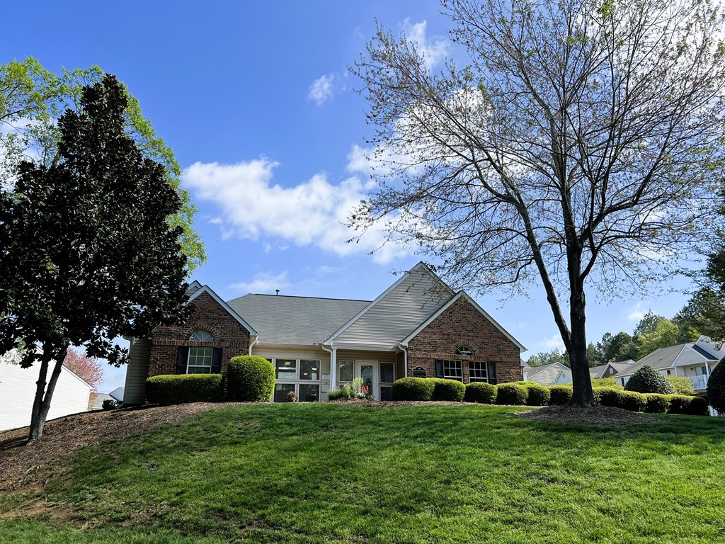 A house with a green lawn and trees in front.