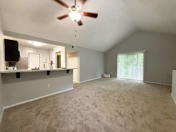 A spacious room with a ceiling fan and a flat screen TV mounted on the wall.