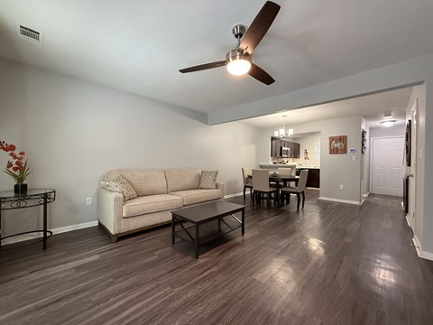 A living room with a beige couch, a coffee table, and a ceiling fan.