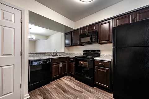 A kitchen with black appliances and wooden cabinets.