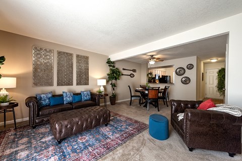 A living room with a brown leather couch and a blue ottoman.