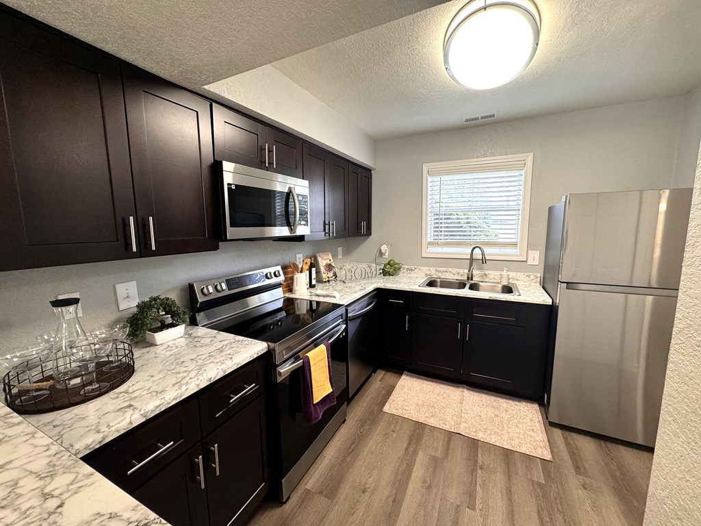 A kitchen with dark wood cabinets and a marble countertop.