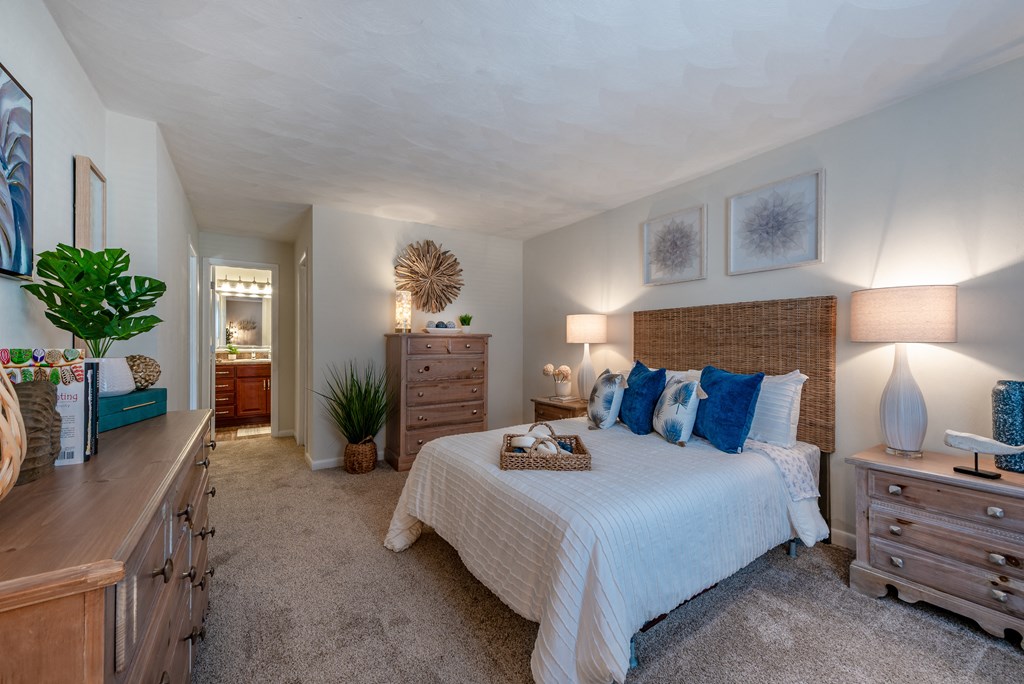 A bedroom with a large bed and a wooden dresser.