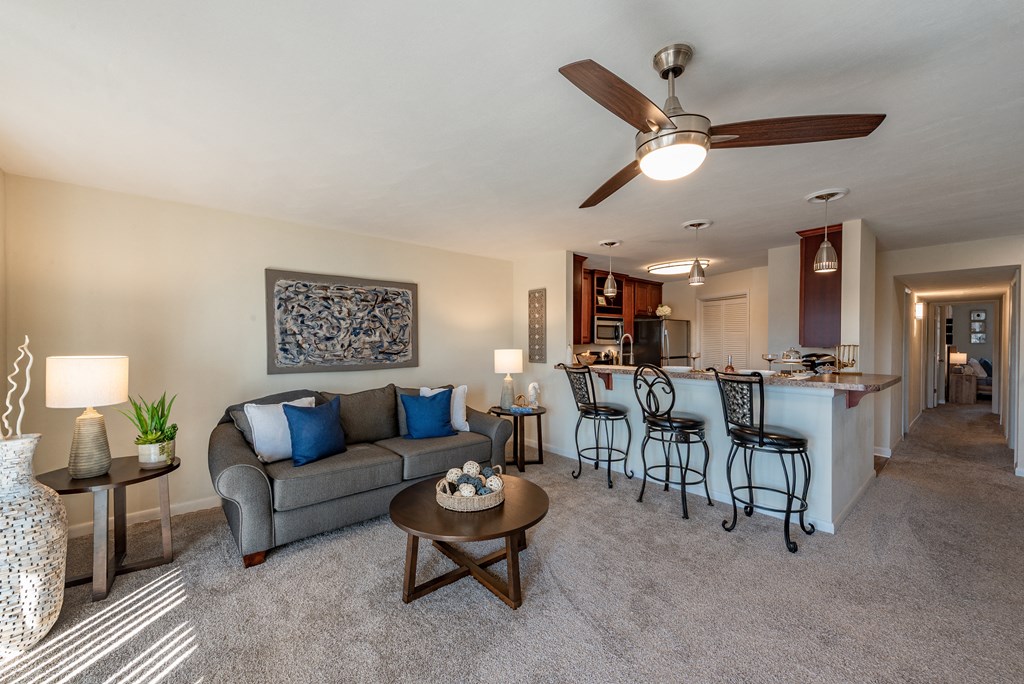 A living room with a grey couch, a coffee table, and a ceiling fan.