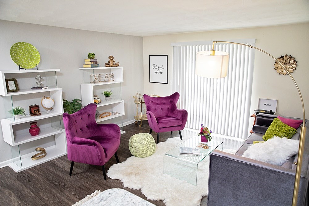 A living room with a purple chair and a glass table.