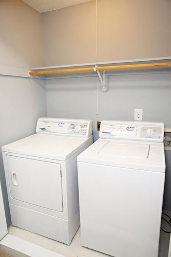 an empty laundry room with two washers and a dryer