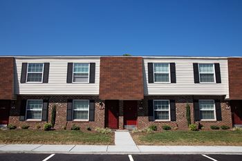 A row of townhouses with red doors and black shutters.