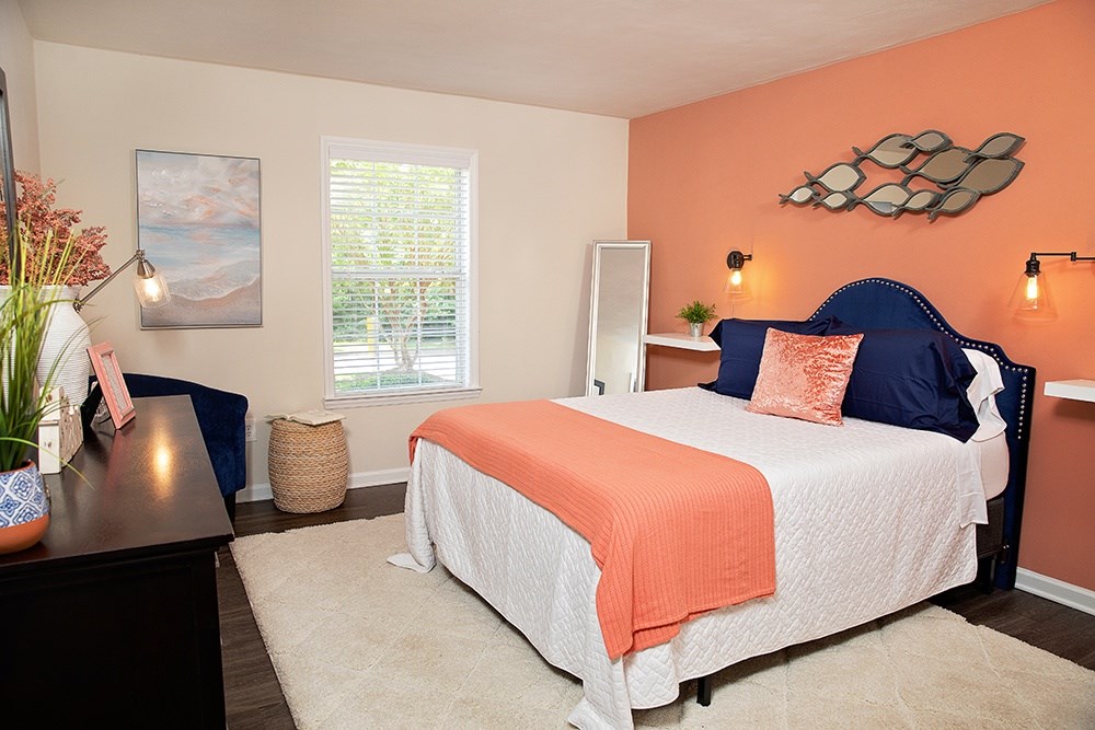 A bedroom with a bed, nightstand, and a painting on the wall.