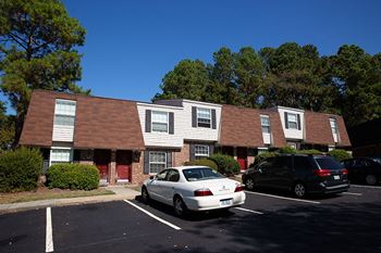 a photo of the front of a building with a parking lot in front of it