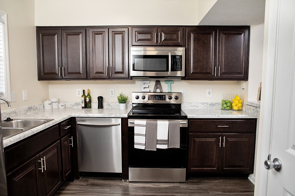 A kitchen with dark brown cabinets and a black stove top oven.