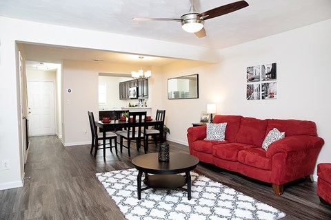 A living room with a red couch and a dining table.