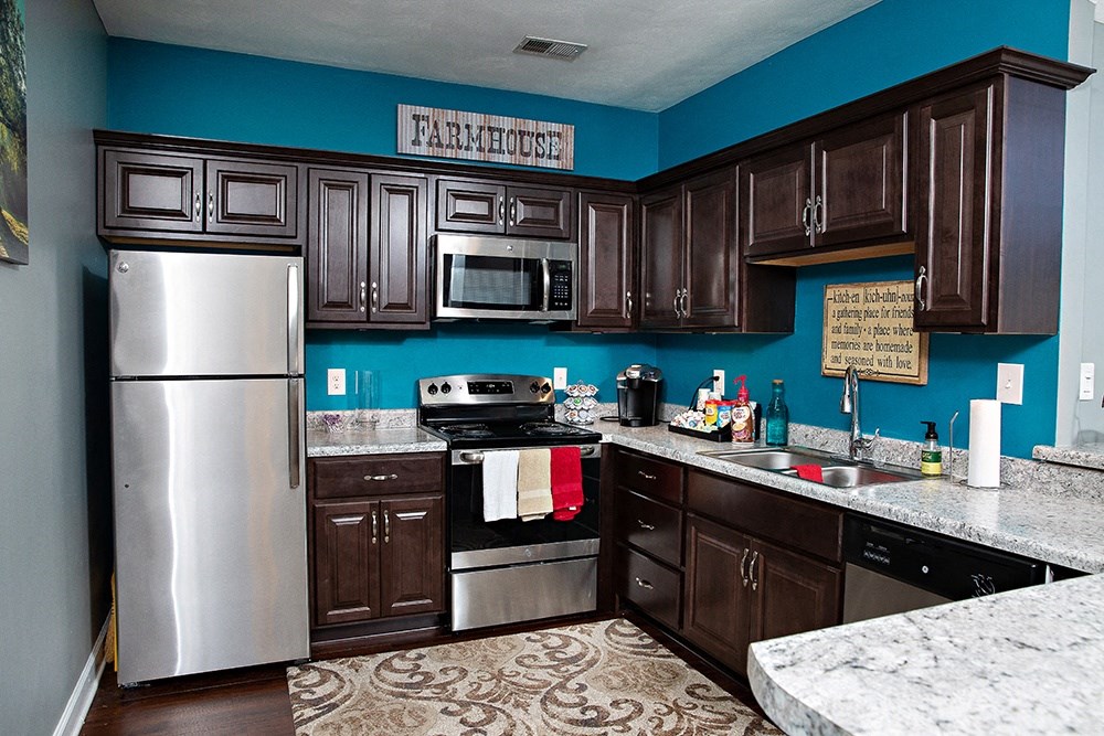 a kitchen with dark cabinets and a blue wall