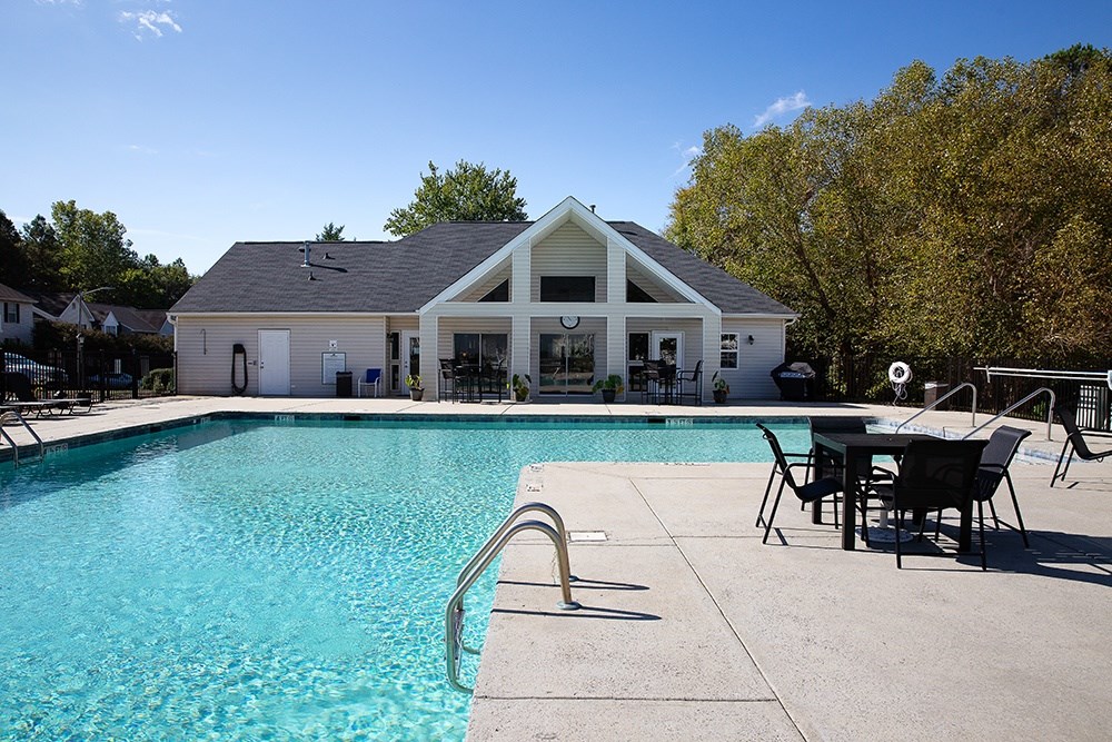 A pool with a slide and a house in the background.