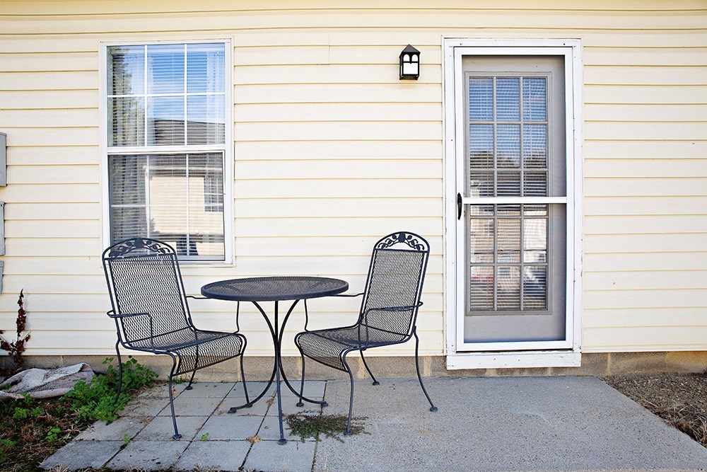 a patio with a table and chairs in front of a house