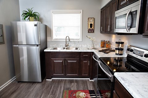 A kitchen with a stainless steel refrigerator and dark brown cabinets.