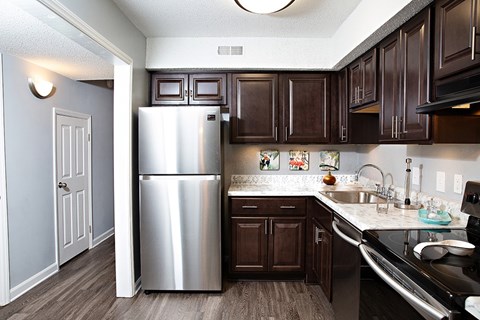 A kitchen with a stainless steel refrigerator and dark brown cabinets.
