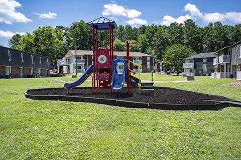 A playground with a red and blue slide and a blue and yellow structure.