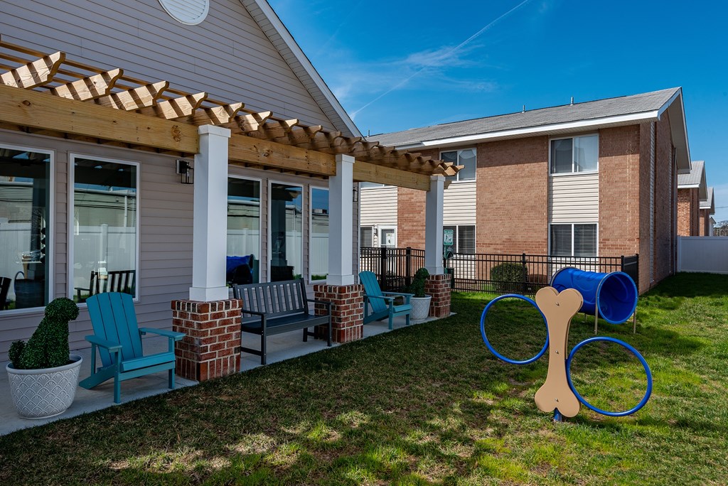 A dog bone sculpture is in the front yard of a house with a wooden pergola.