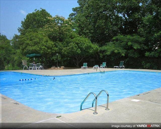 a swimming pool with chairs around it and trees
