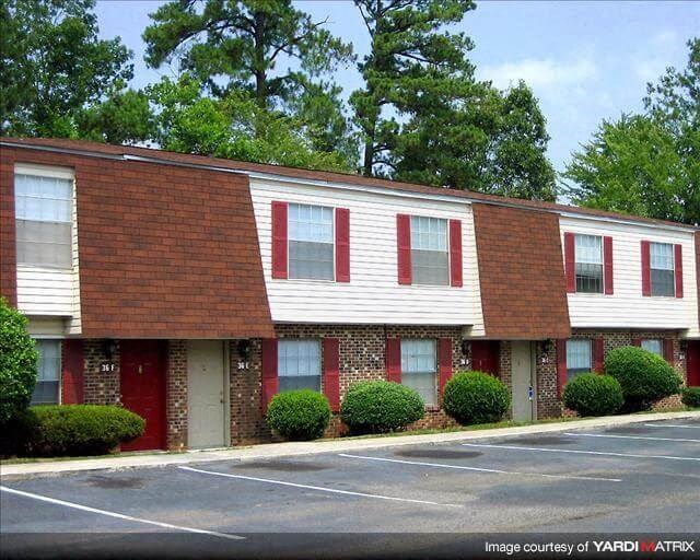 a red and white apartment building in a parking lot