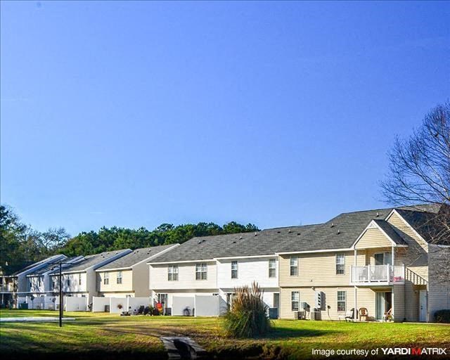 a row of houses sitting on top of a lush green field