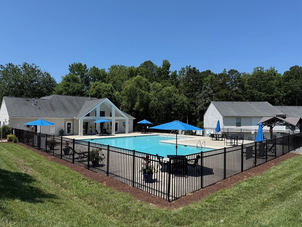 A pool surrounded by a black fence with a house in the background.