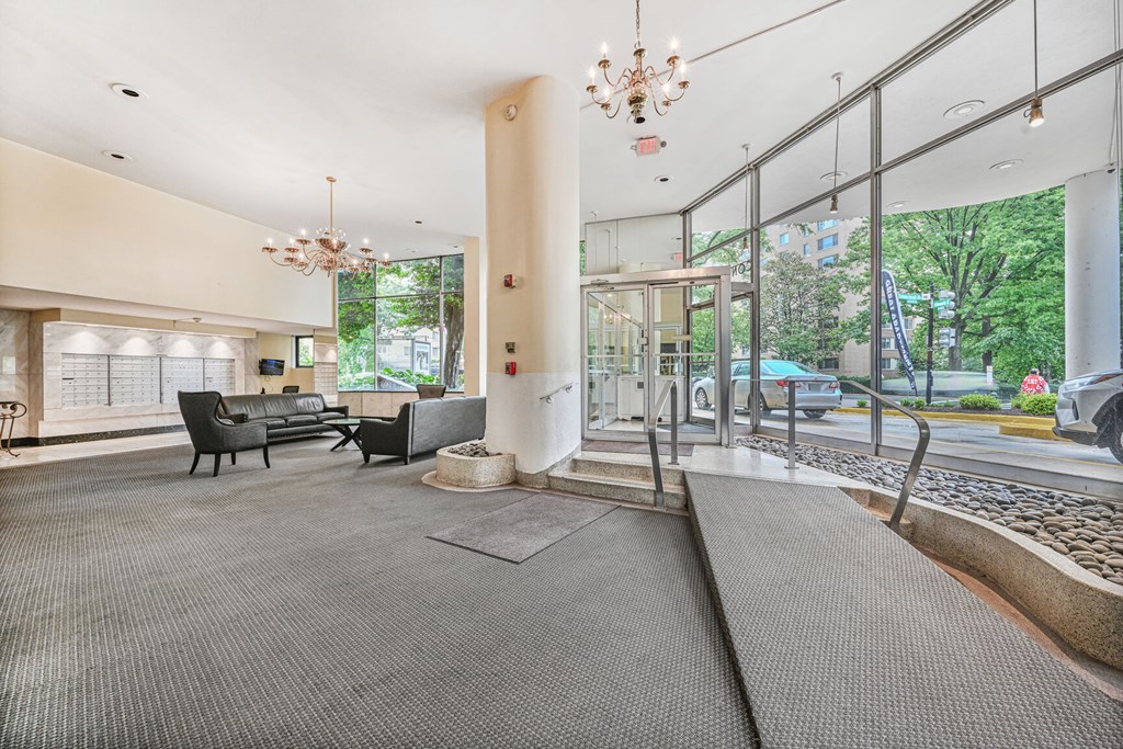 A large, open lobby with a grey carpet and a chandelier hanging from the ceiling.