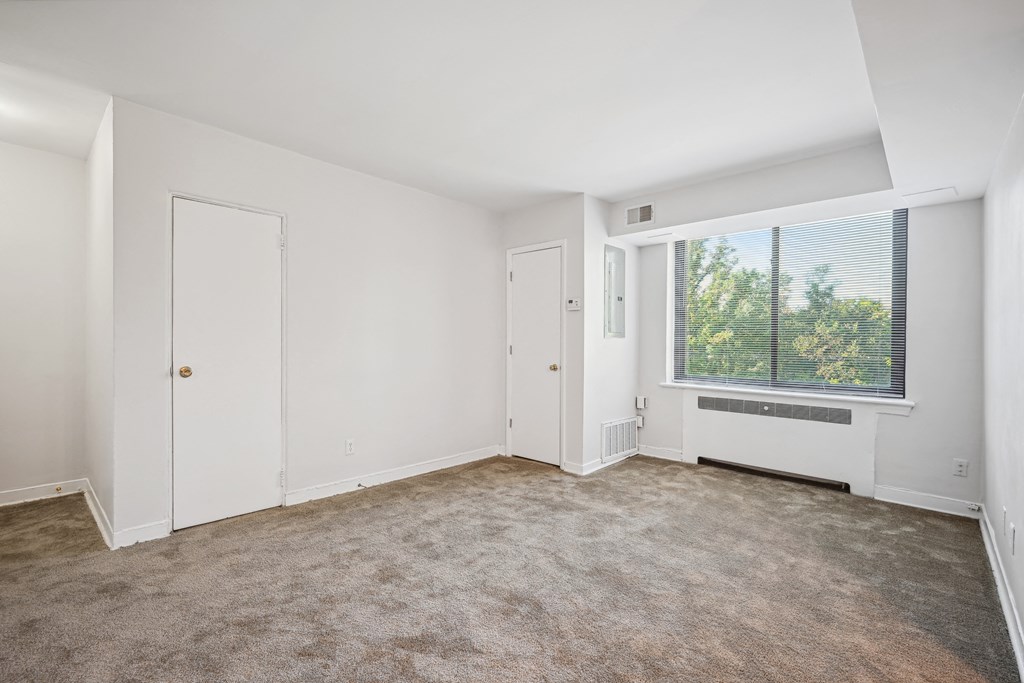 an empty living room with a large window and white walls