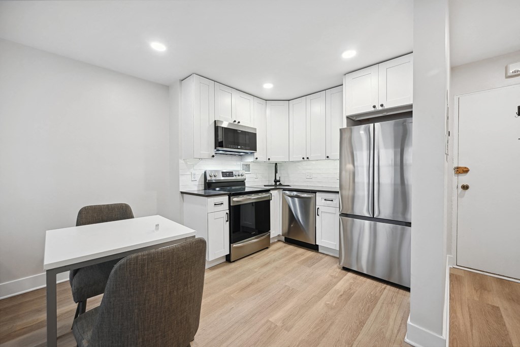 a white kitchen with stainless steel appliances and white cabinets