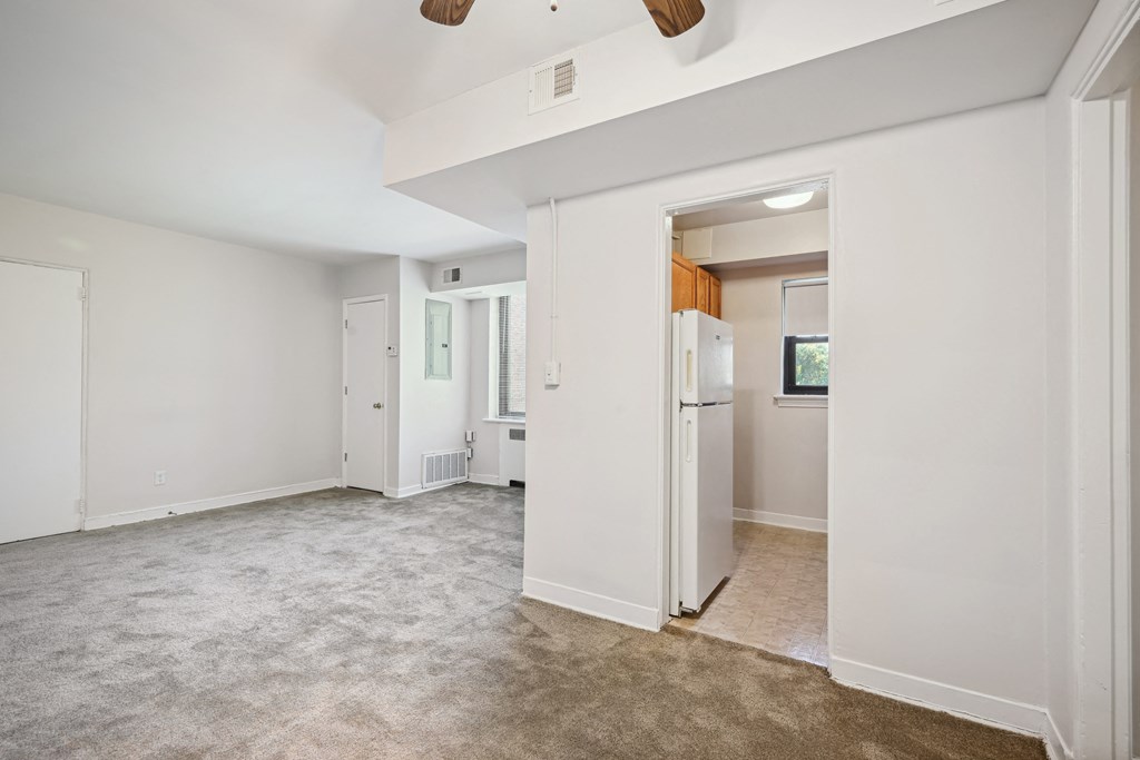 a living room with white walls and a white refrigerator