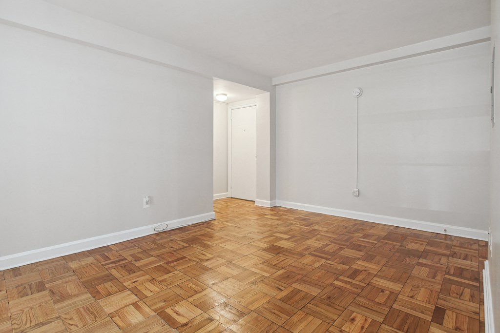 a bedroom with hardwood floors and white walls