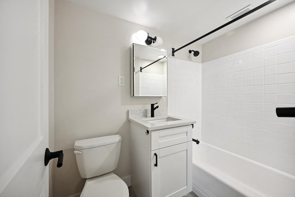 a white bathroom with a toilet and a sink and a tub