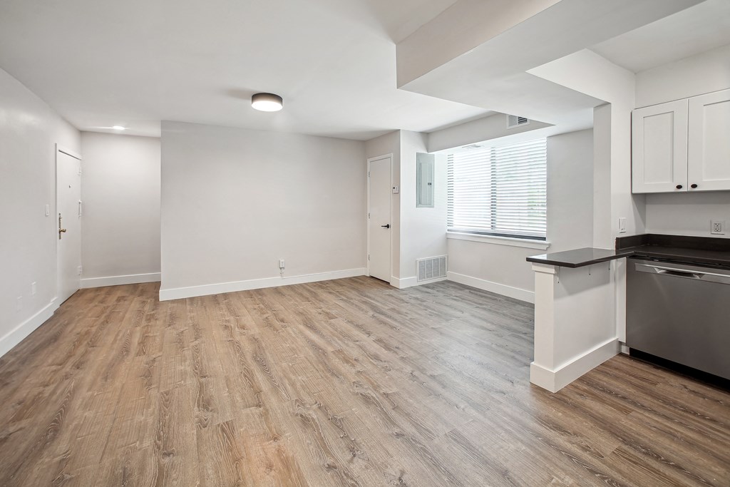 an empty kitchen and living room with wood flooring and a large window