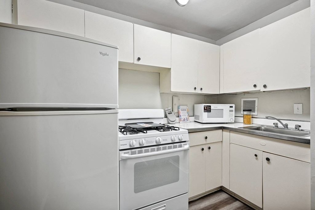 an empty kitchen with white appliances and white cabinets