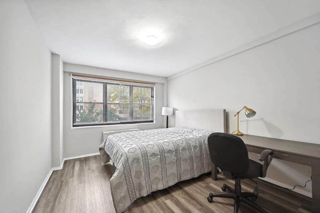 a bedroom with a bed and a desk and a window