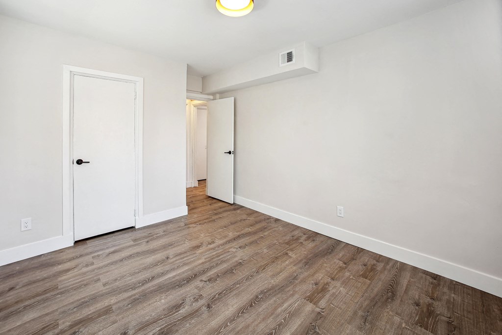 an empty room with white walls and wood flooring