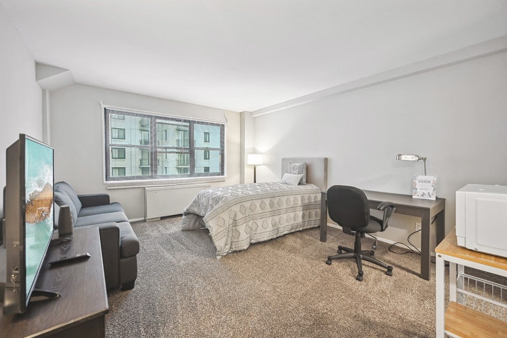 a bedroom with a bed and a desk and a window