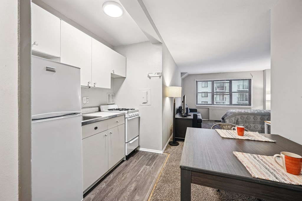 a kitchen and living room with white appliances and a wooden table