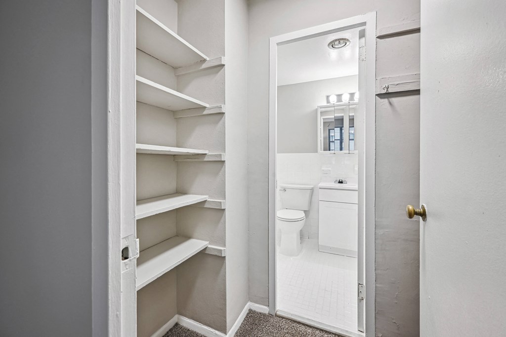 a small bathroom with white cabinets and a door to the toilet