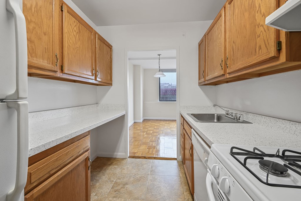 A kitchen with white appliances and wooden cabinets.
