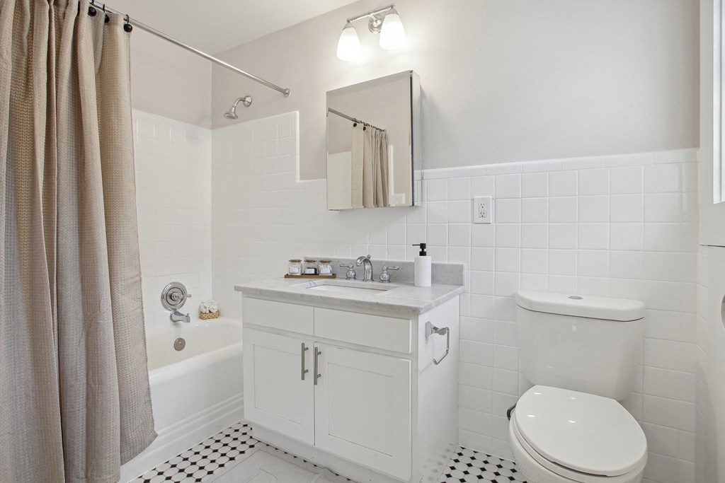 a bathroom with white fixtures and a black and white tiled floor