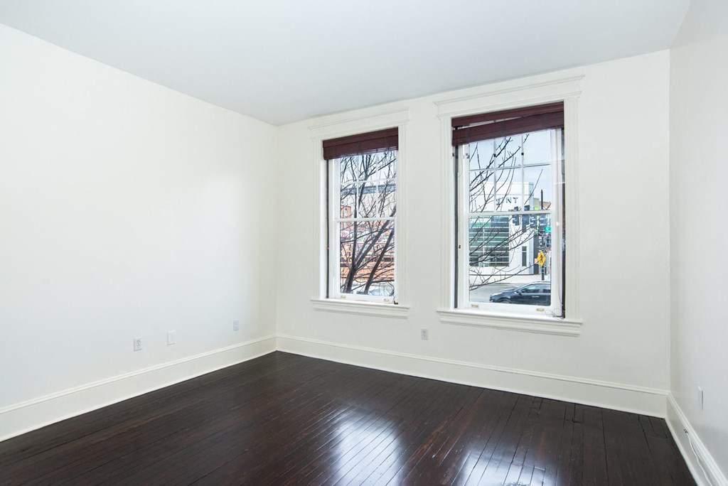 a living room with white walls and three windows