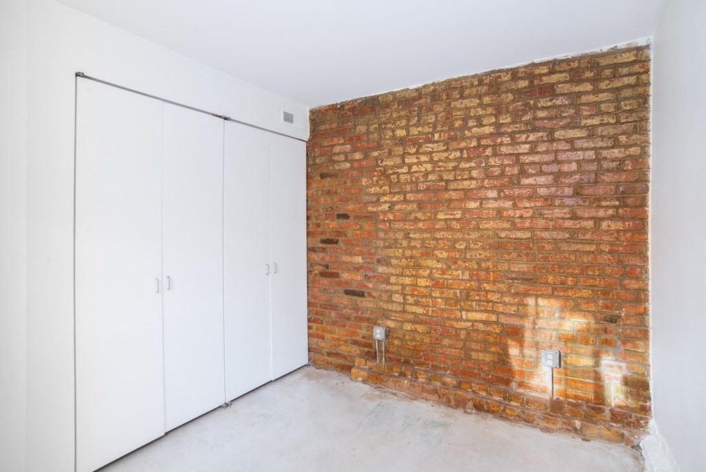an exposed brick wall in a room with white cabinets