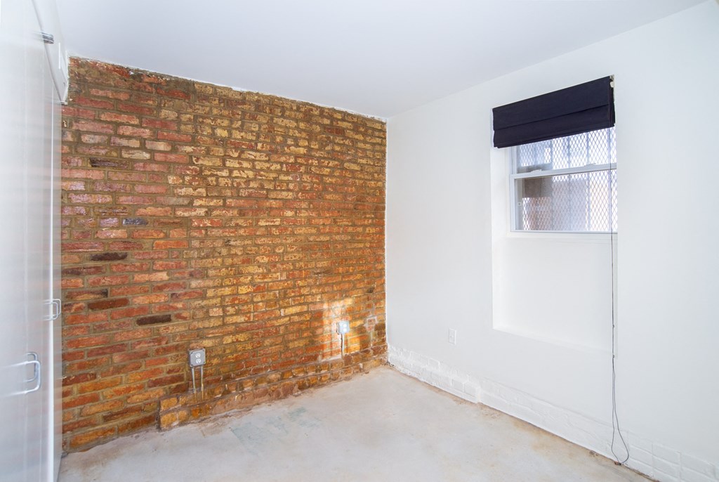 an empty room with a brick wall and a window