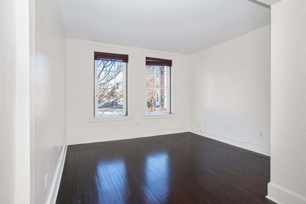 a living room with wood floors and two windows