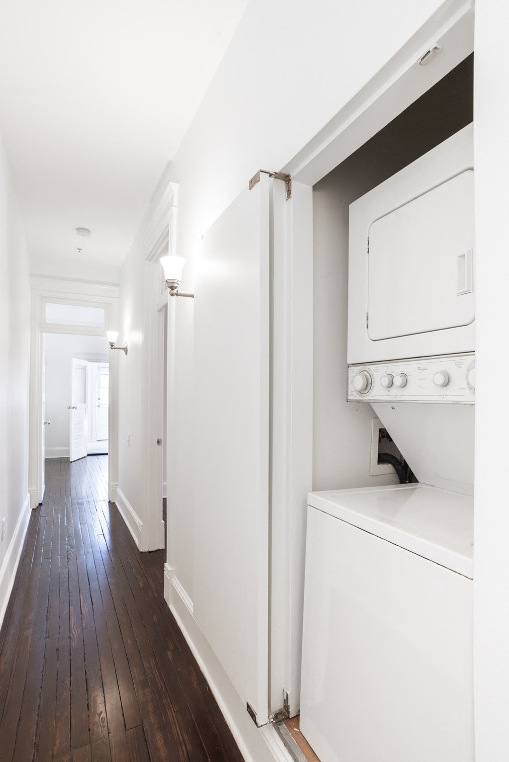a white laundry room with a washer and dryer and a wooden floor