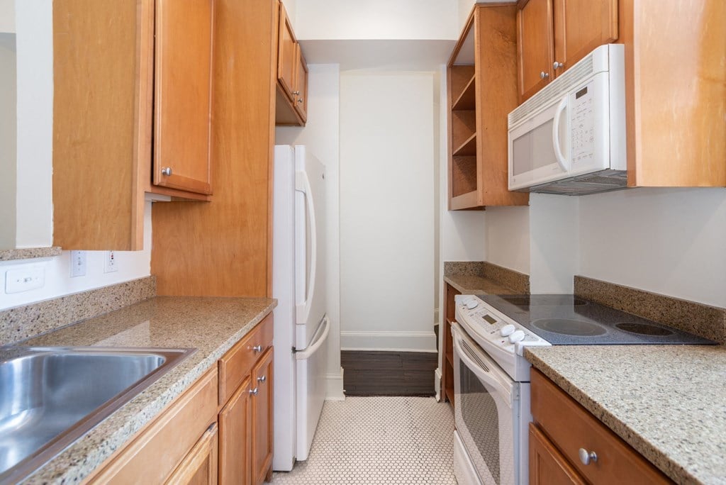 a kitchen with wood cabinets and white appliances and granite counter tops
