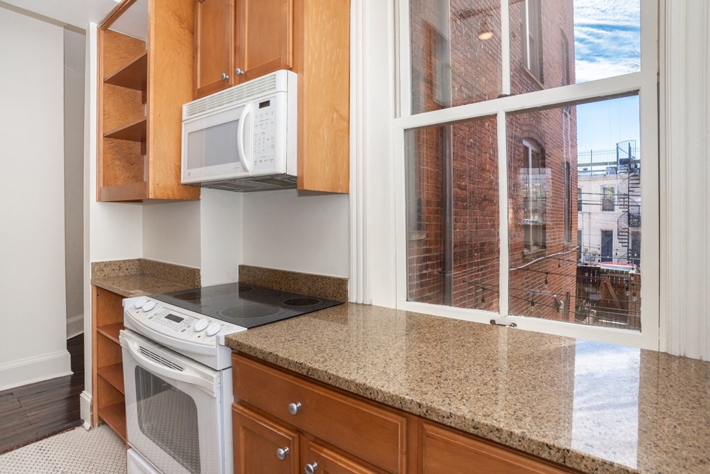 a kitchen with a window and a counter with a stove and a microwave