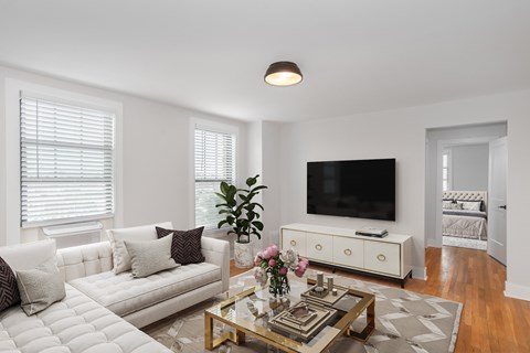 A living room with a white couch, a coffee table, and a flat screen TV.