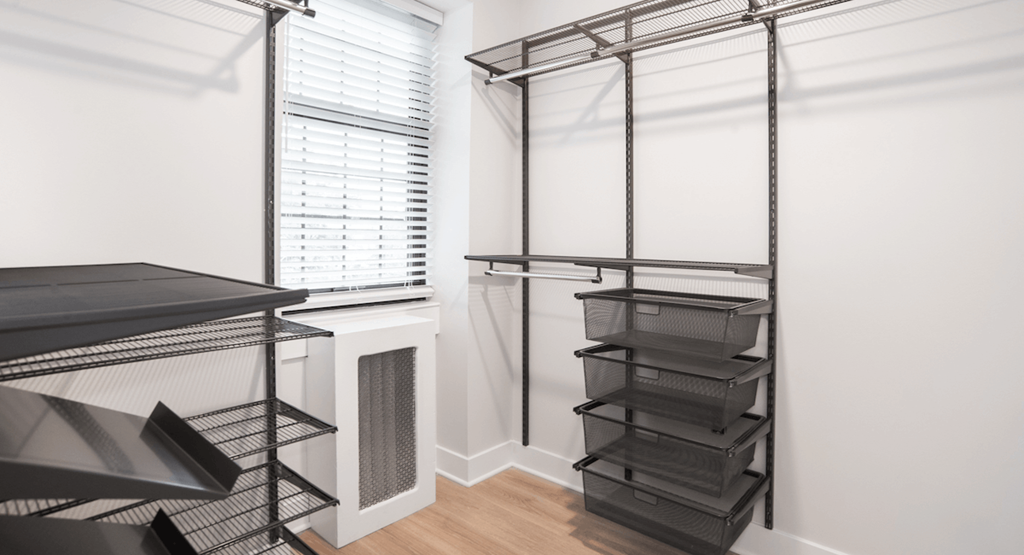 a walk in closet with black shelves and a window